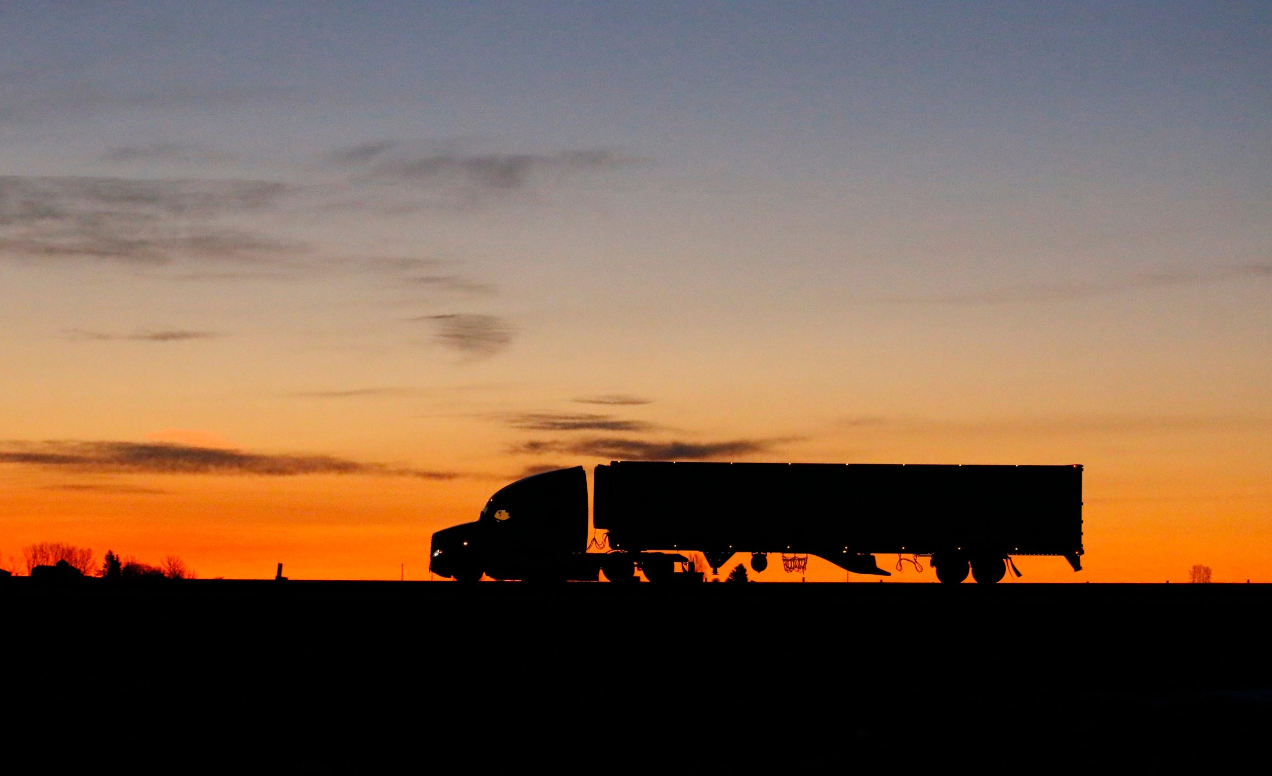 a semi-truck silhoutted against a sunset