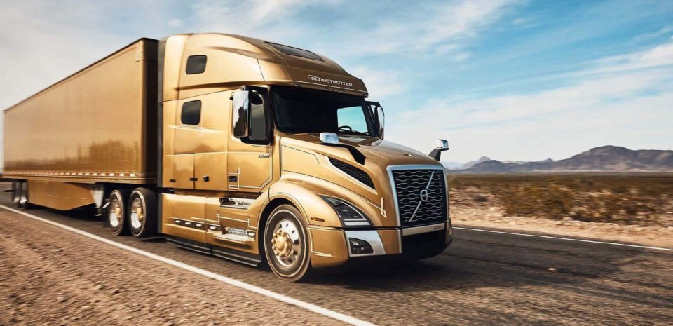 Front end of a gold-colored semi-truck on the highway.