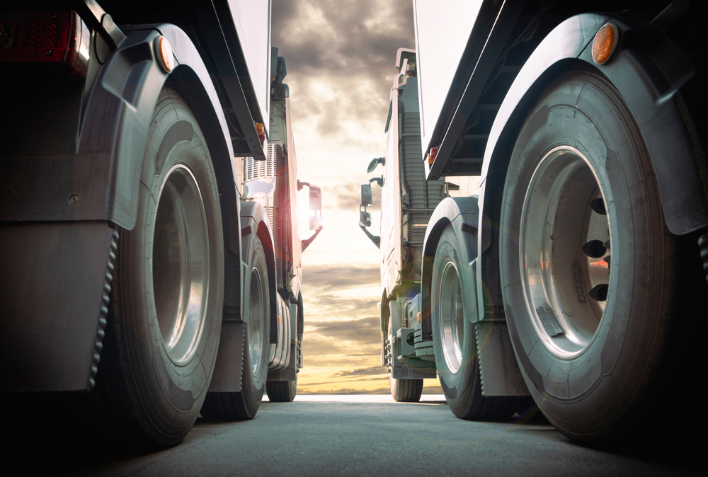 Ground view of two semi-trucks at the tire level.