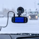 Image of a truck dash cam stuck to the inside of a windshield. Snow and rainy conditions outside.