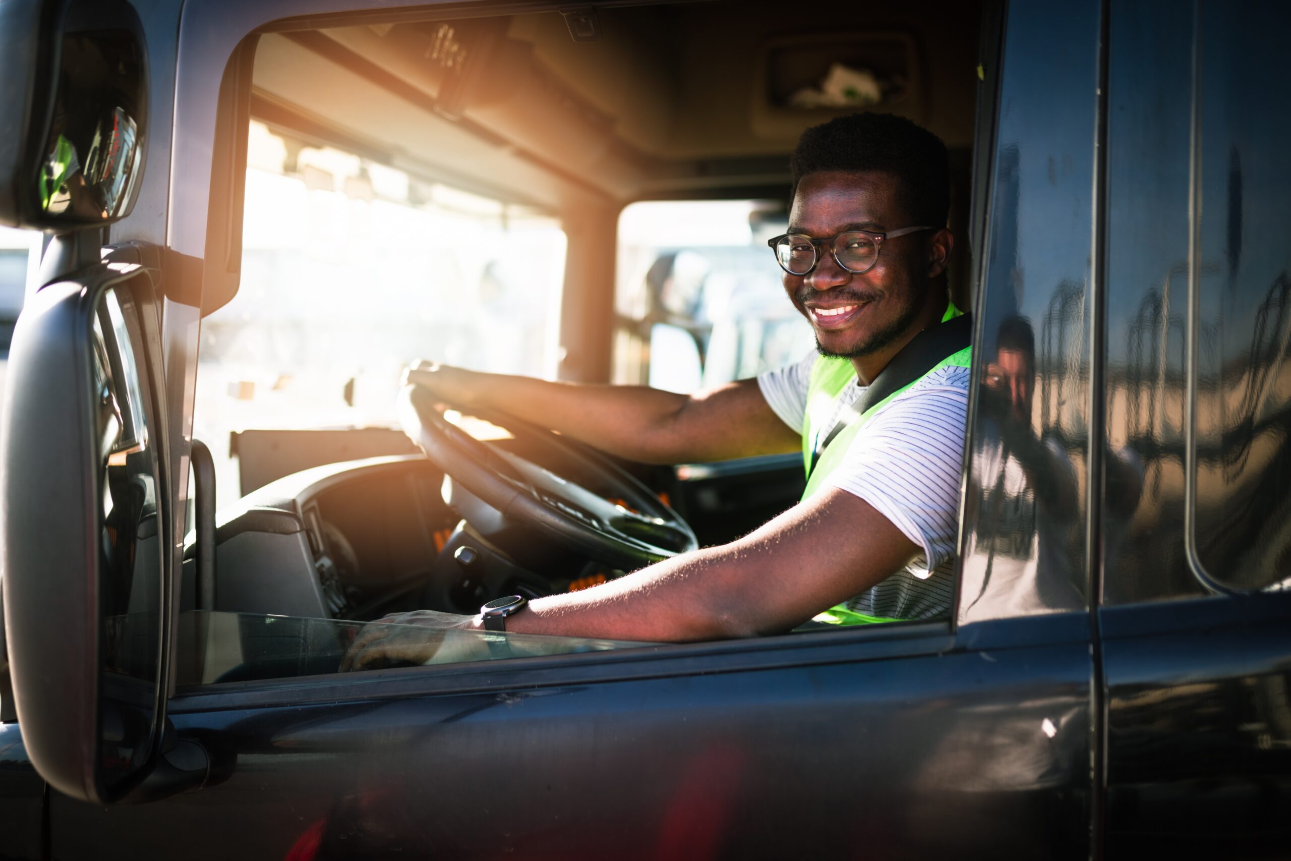 Young male driver in the seat of a semi-truck.
