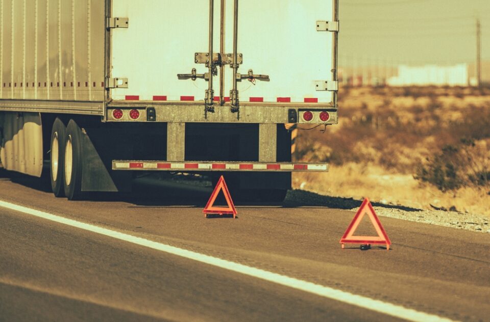 Semi-truck on the side of the road with triangular safety reflectors