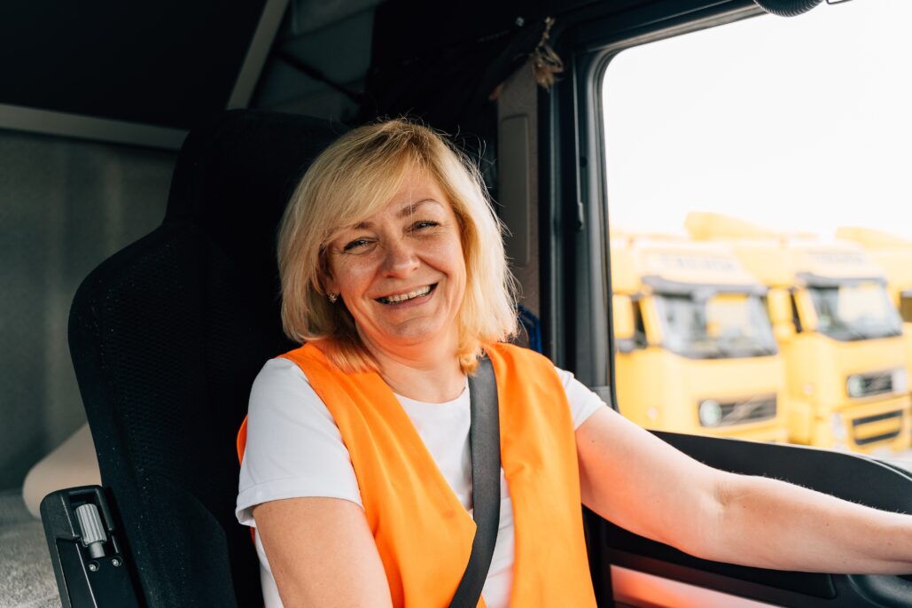 Woman in orange safety vest in the cab of a semi-truck