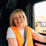 Woman in orange safety vest in the cab of a semi-truck