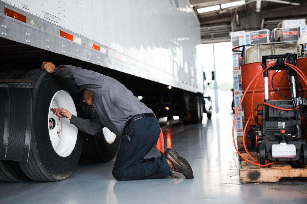 Man checking tire pressure on a semi-truck.