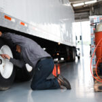 Man checking tire pressure on a semi-truck.