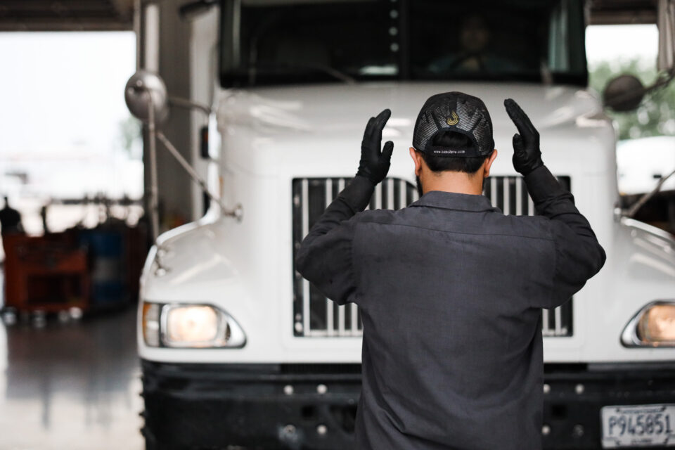 A mechanic stands in front of a white semi-truck.