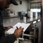 Mechanic reviews a checklist on a clipboard.