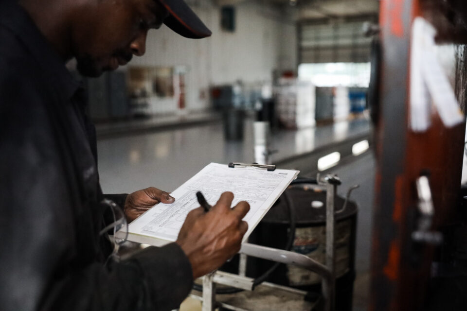 Mechanic reviews a checklist on a clipboard.
