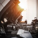 Truck with open hood ready for engine inspection at sunset.