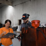 two workers review a clipboard beside industrial equipment