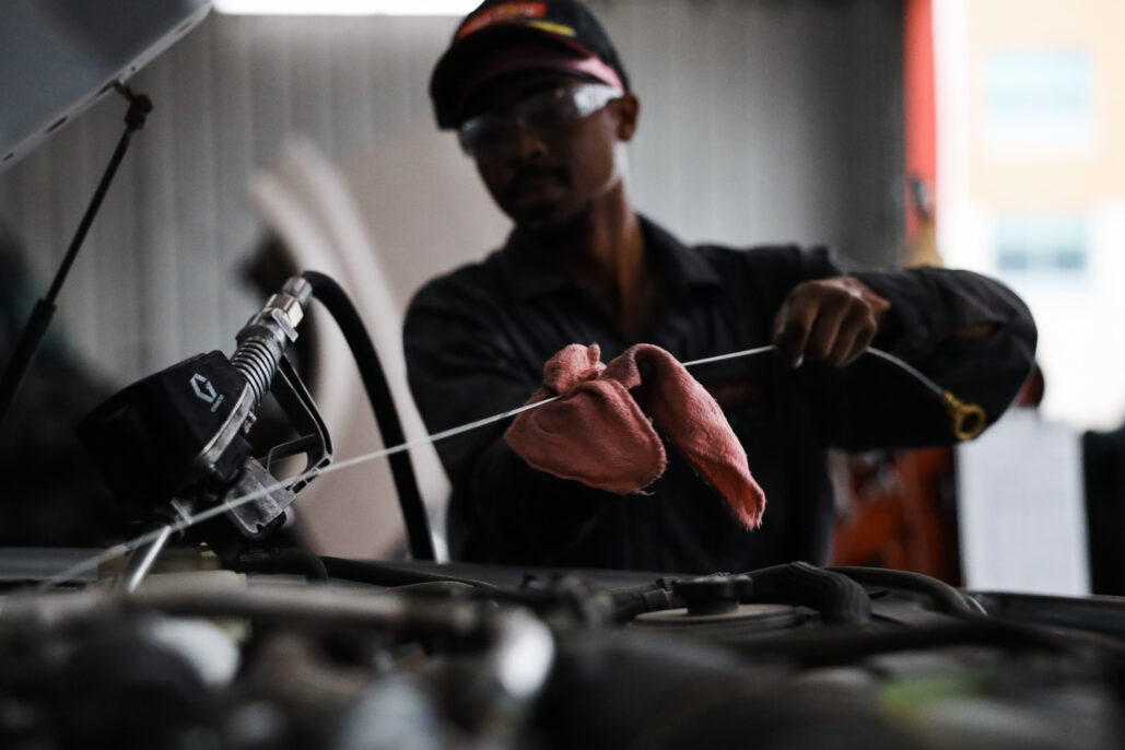 Mechanic checking oil level under a car hood