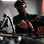 Mechanic checking oil level under a car hood