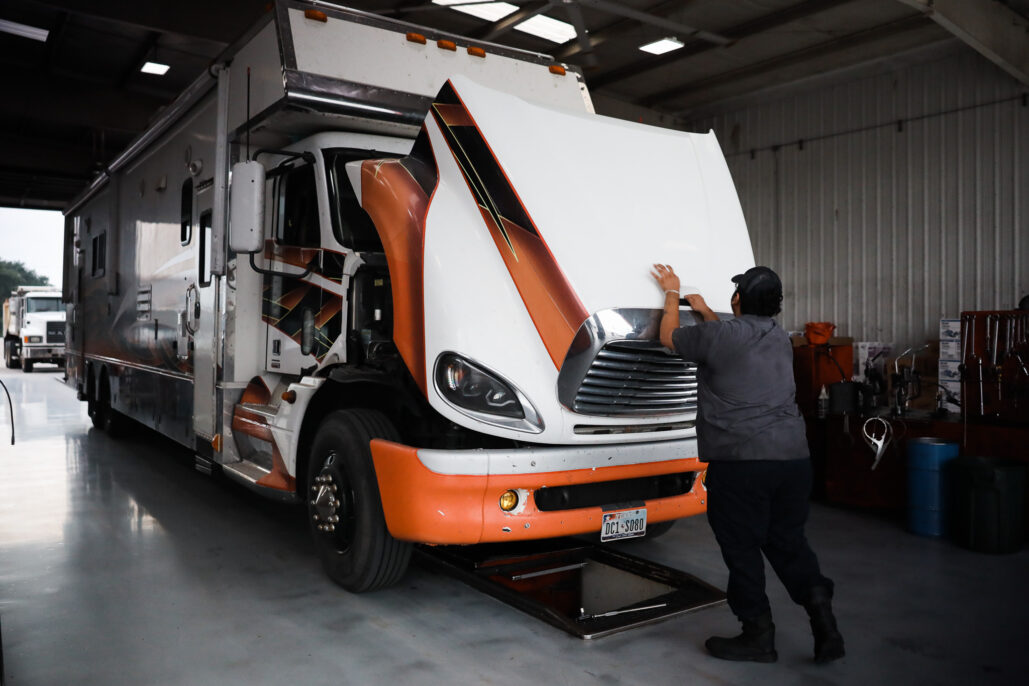 Worker inspecting the front of a large truck inside a garage