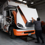 Worker inspecting the front of a large truck inside a garage