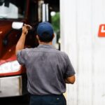 worker directing a red truck near a service bay