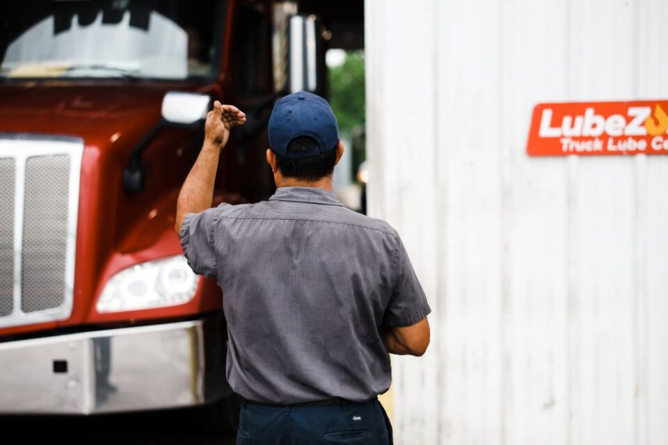 worker directing a red truck near a service bay